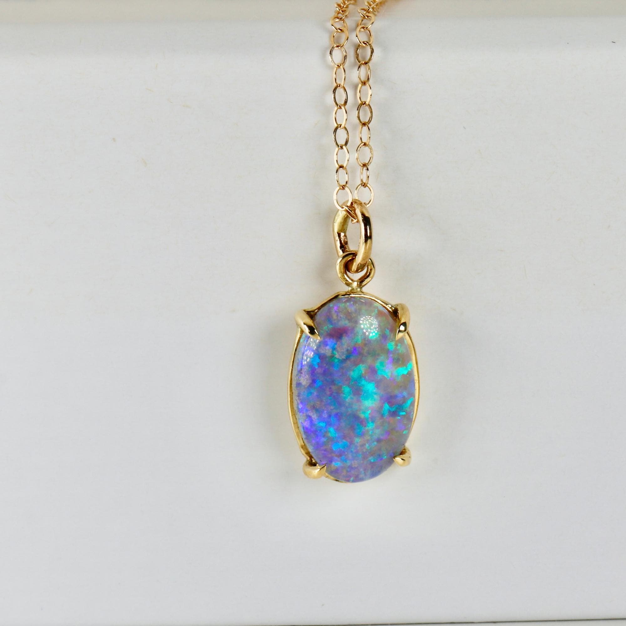White background: 14k solid gold necklace with an Australian boulder opal pendant, displaying vibrant flashes of blue fire.