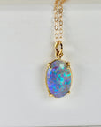 White background: 14k solid gold necklace with an Australian boulder opal pendant, displaying vibrant flashes of blue fire.