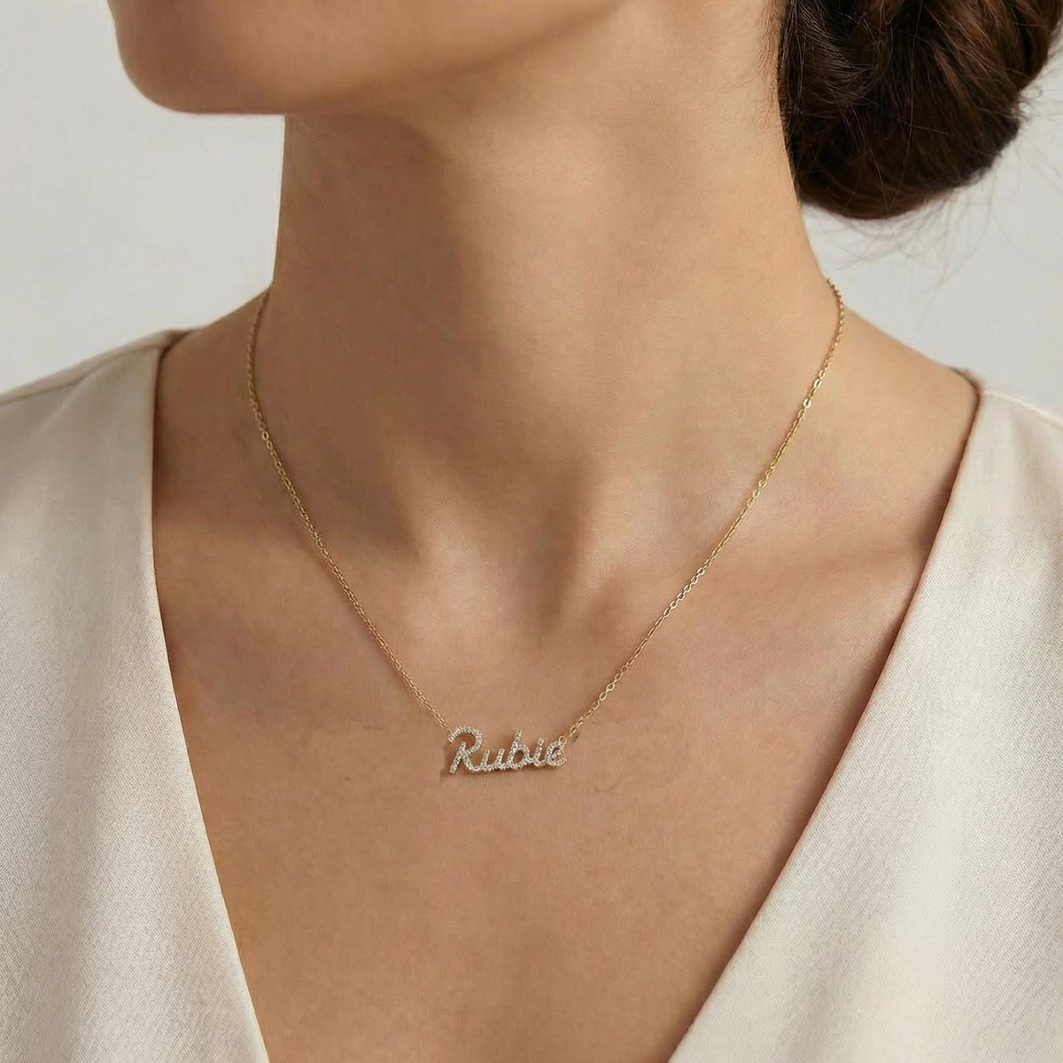 Woman wearing a personalized 14K gold diamond name necklace.