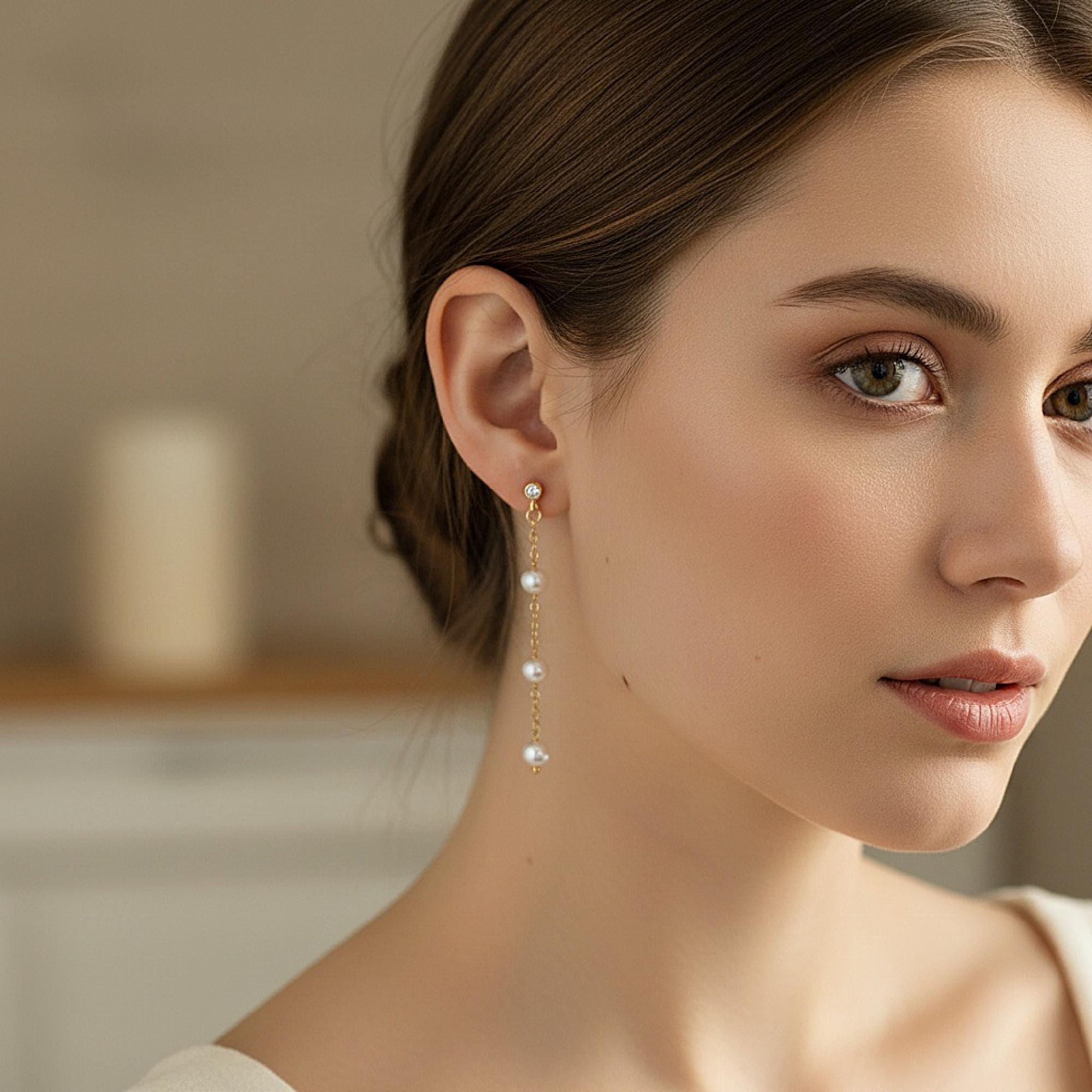 Gold filled pearl drop earrings worn on ear with zircon stud detail