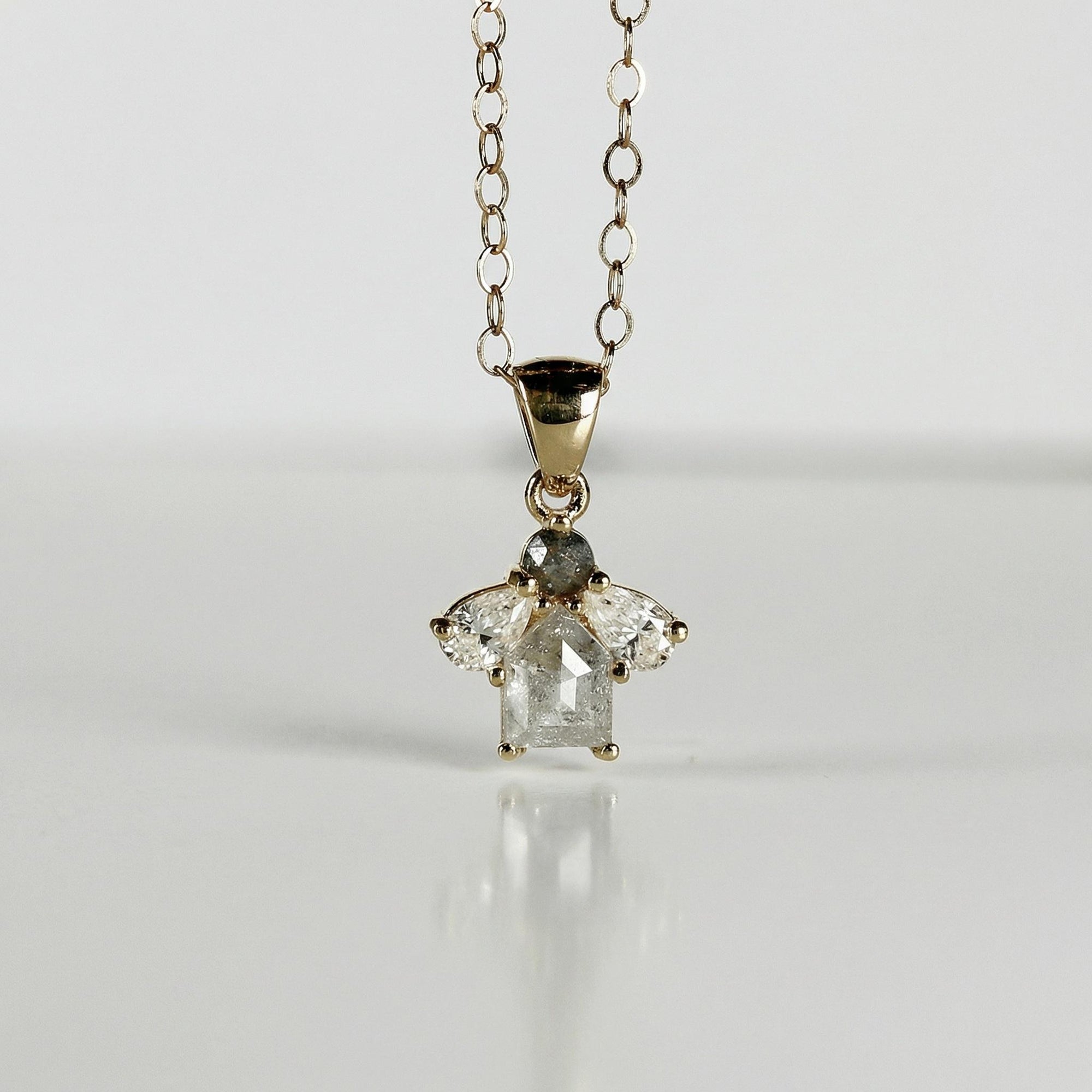 14k solid gold cluster necklace featuring a center rose cut salt and pepper diamond surrounded by pear-shaped moissanites on a white background.