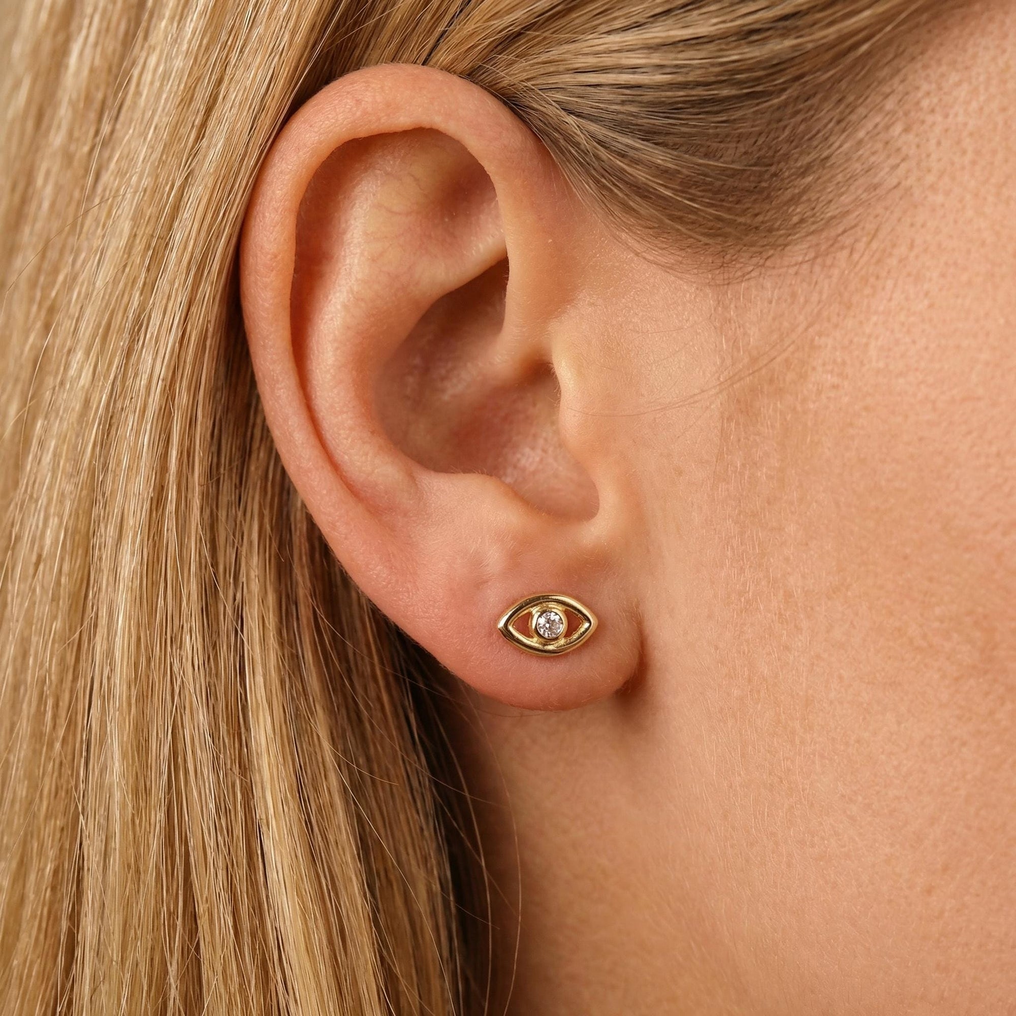 14k gold evil eye flat back earring styled on model ear stack