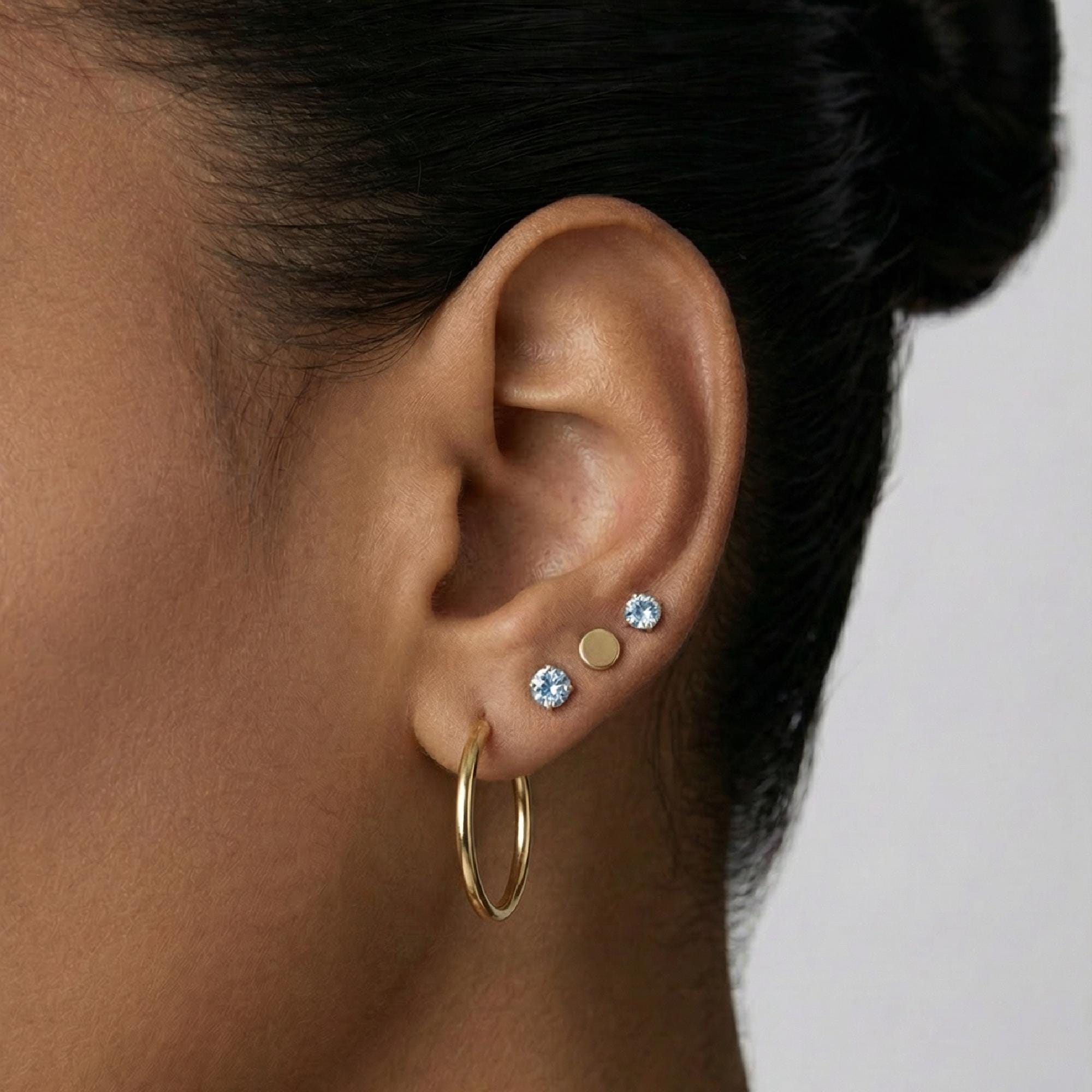 Model wearing 14k gold aquamarine stud earrings, dainty March birthstone jewelry