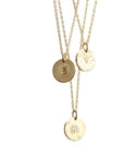 Three gold necklaces with hammered disc pendants, each featuring a different initial: S, V, and H.