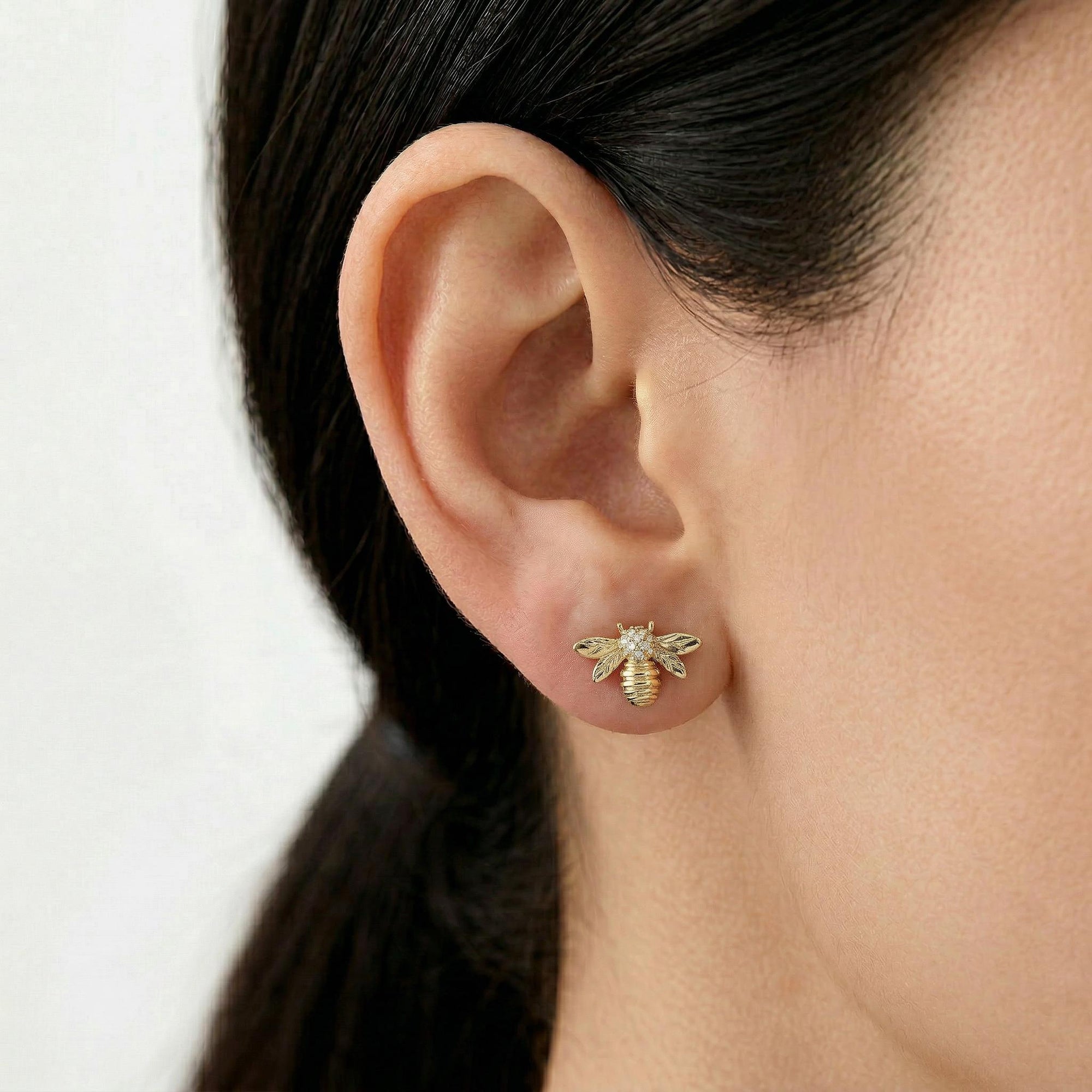 gold bee stud earrings with diamonds worn on ear, nature inspired dainty jewelry for women