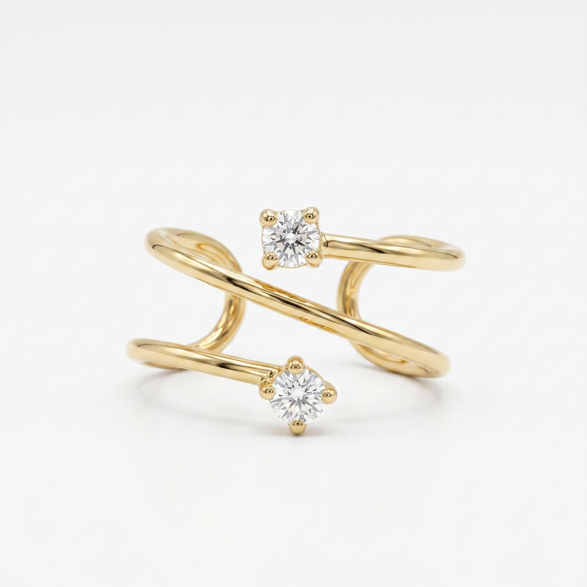 A gold ear cuff with two clear, round, prong-set stones, one on the upper band and one on the lower band, on a white background.