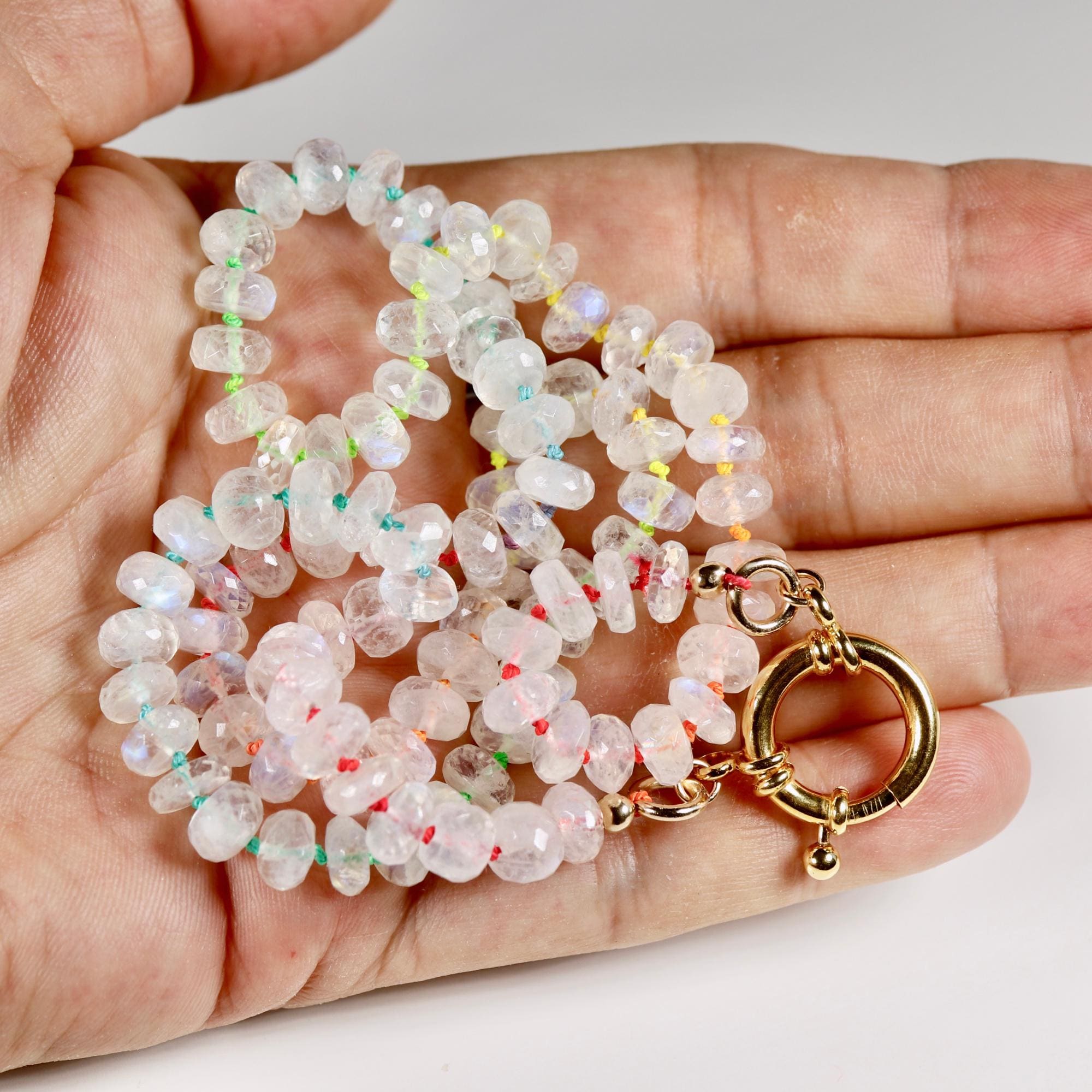Close up of rainbow silk thread and moonstone rondelle beads showing hand knotting detail and gold filled figure eight charm holder clasp.