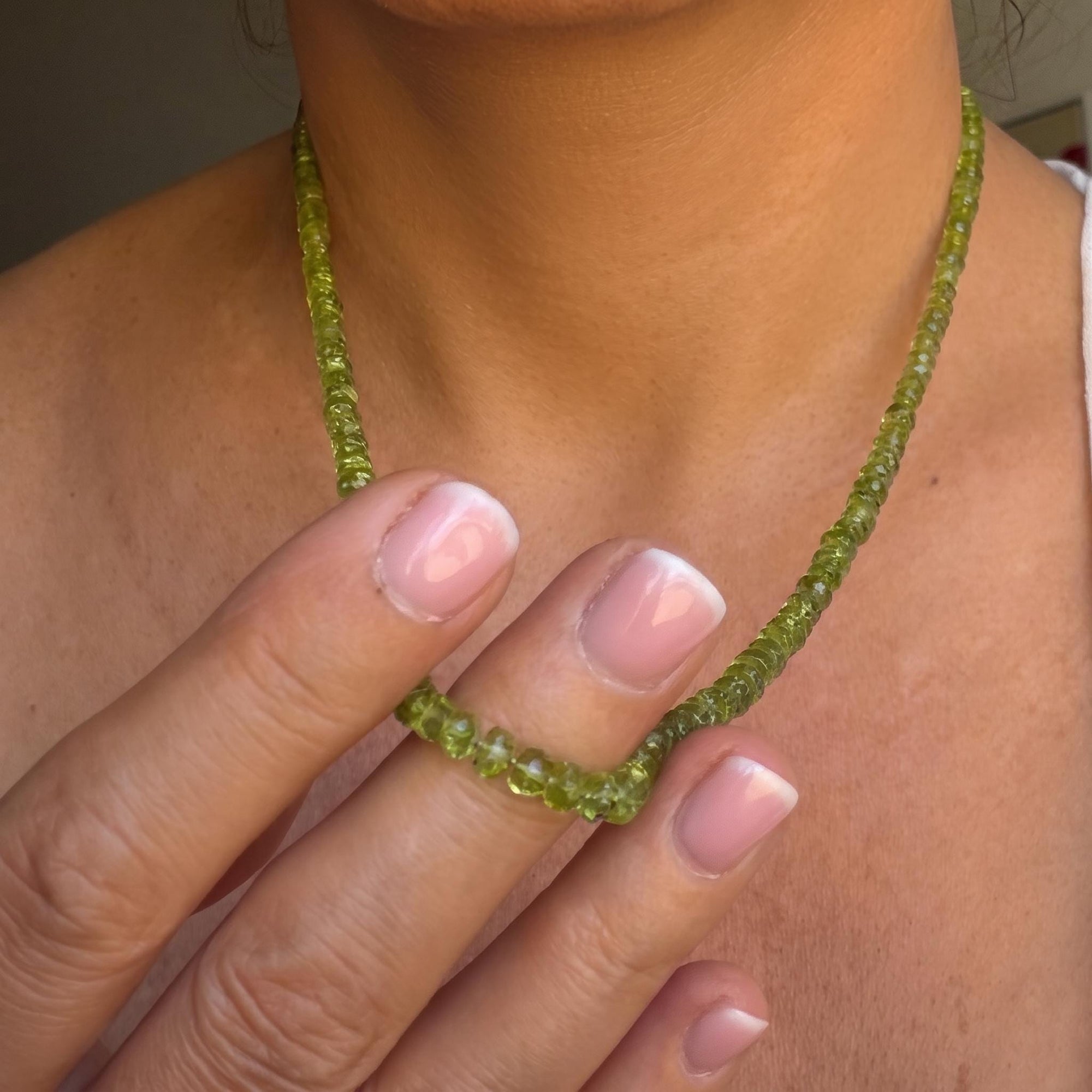 Model is wearing, Peridot August birthstone hand knotted necklace layered with gold chains for a fresh summer look.
