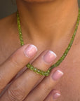 Model is wearing, Peridot August birthstone hand knotted necklace layered with gold chains for a fresh summer look.