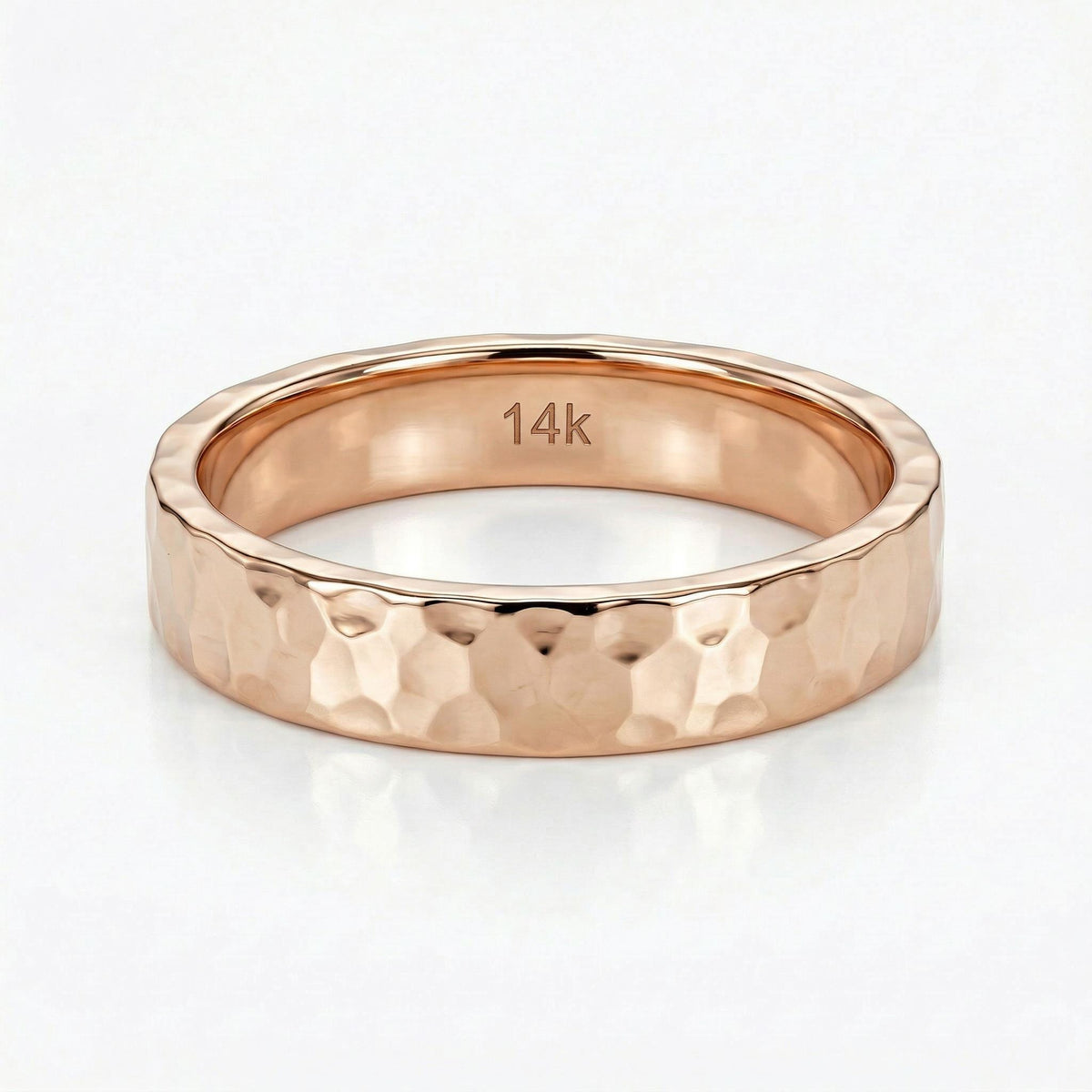 A rose gold hammered band ring with &amp;quot;14K&amp;quot; engraved on the inside.