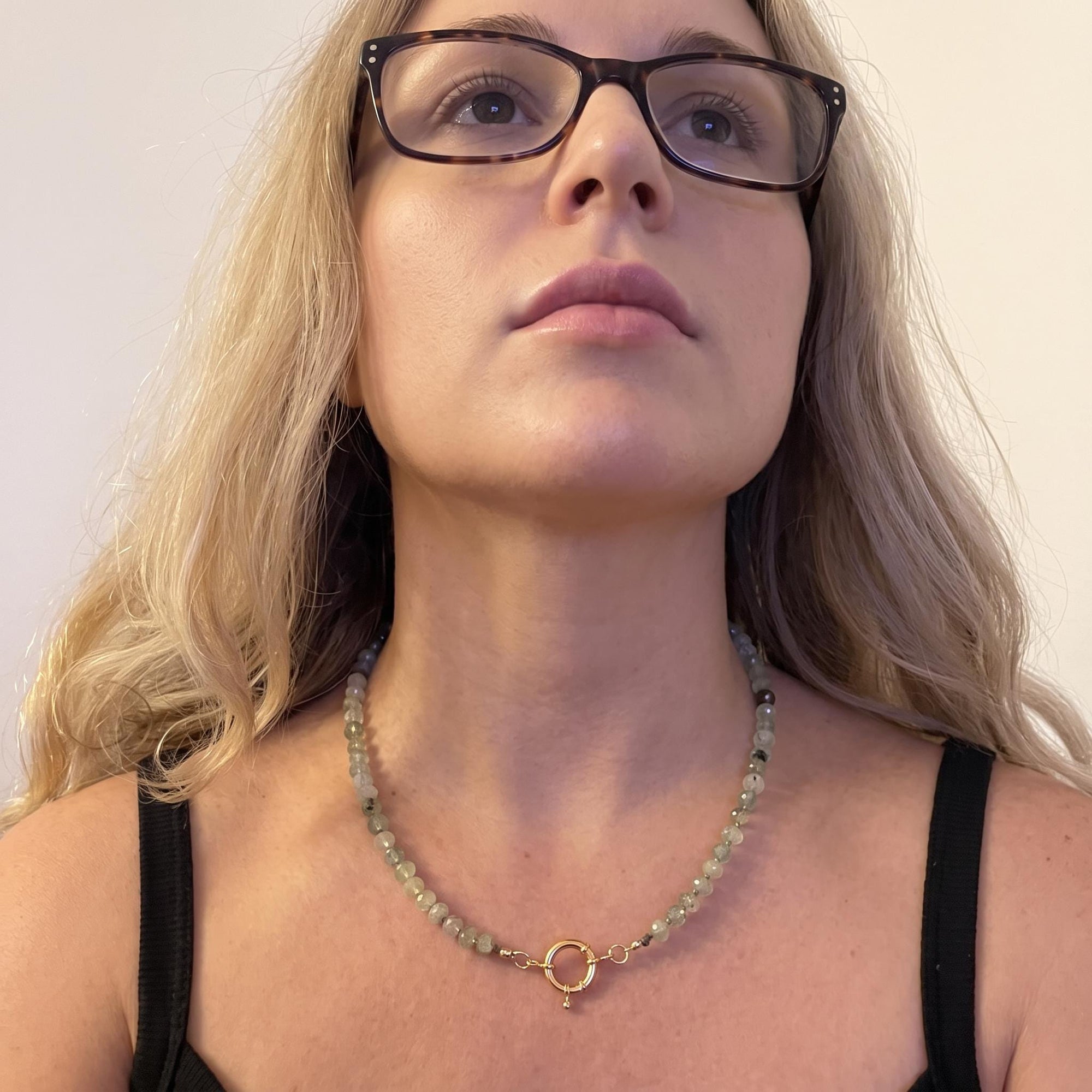 Prehnite silk hand knotted necklace worn at the neckline showing 20 inch length and figure eight charm holder clasp at the front.