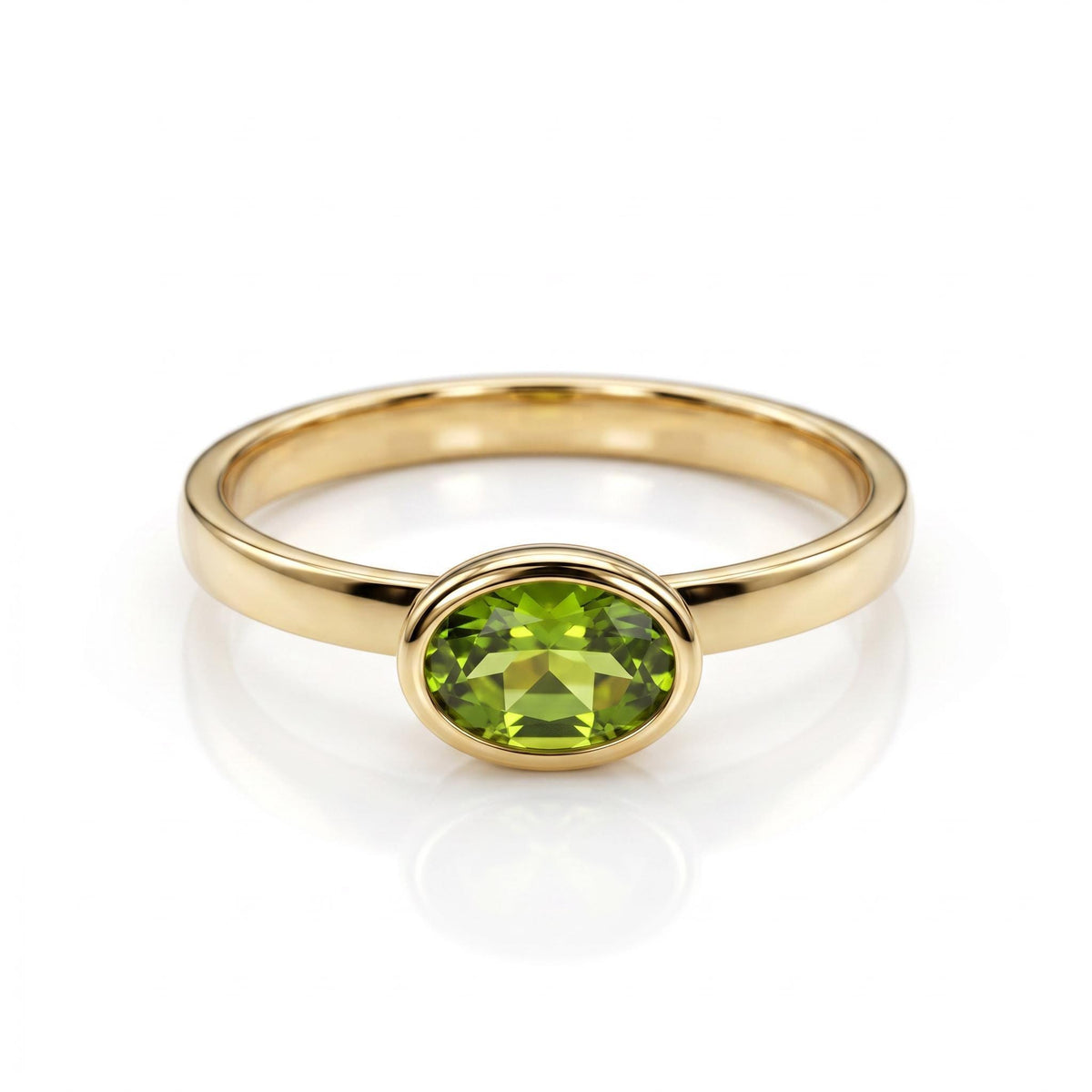 A gold ring with a horizontal oval peridot gemstone in a bezel setting, centered on a white background.