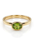 A gold ring with a horizontal oval peridot gemstone in a bezel setting, centered on a white background.