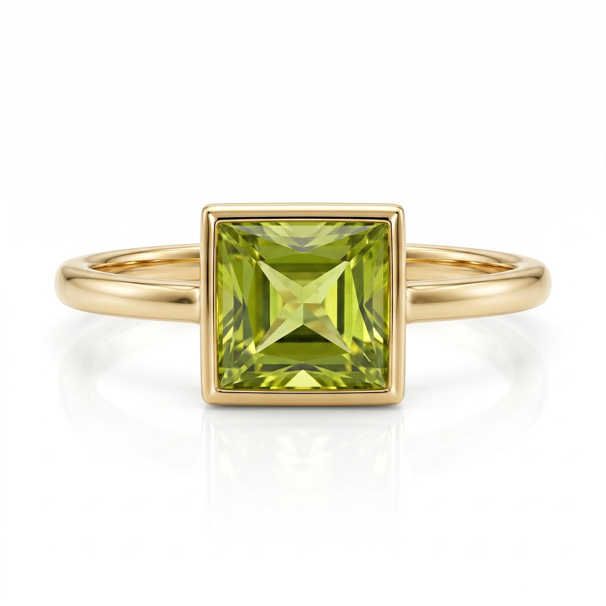 A gold ring with a square-cut peridot stone in a bezel setting, centered on a white background.