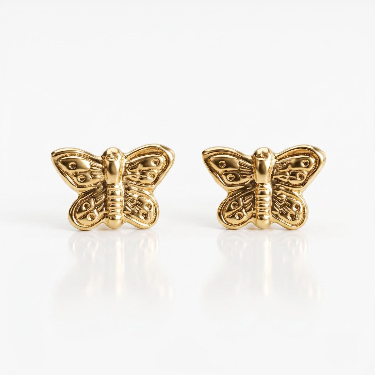 A pair of gold butterfly stud earrings with textured wings and bodies are shown on a white background.
