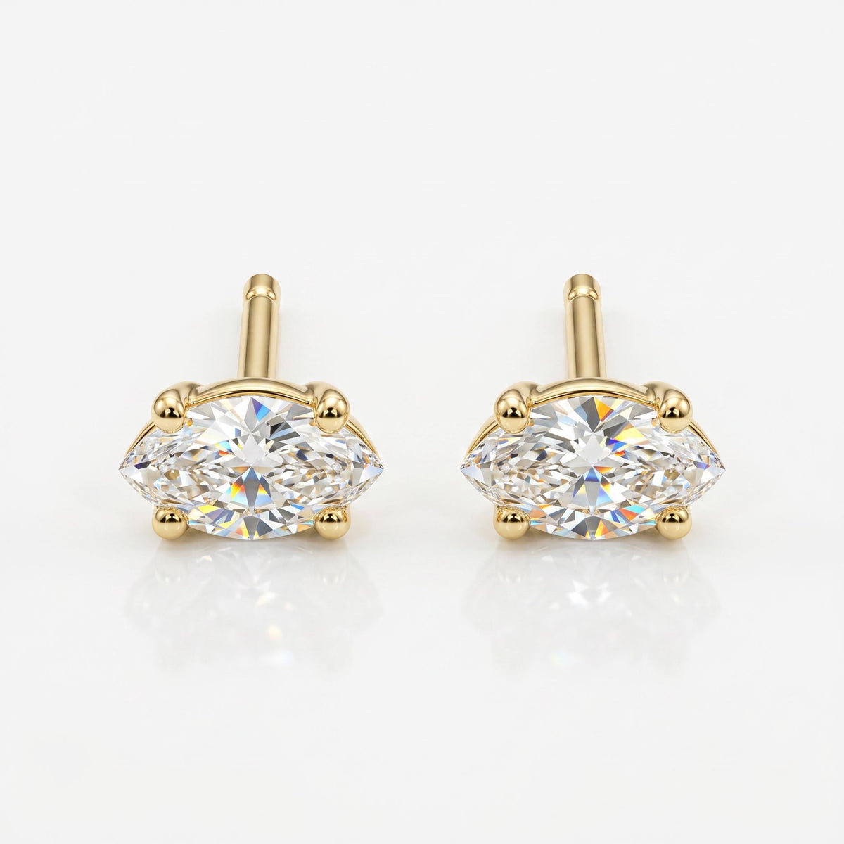 Two gold stud earrings, each with a marquise-cut diamond held by four prongs, are shown on a white background.