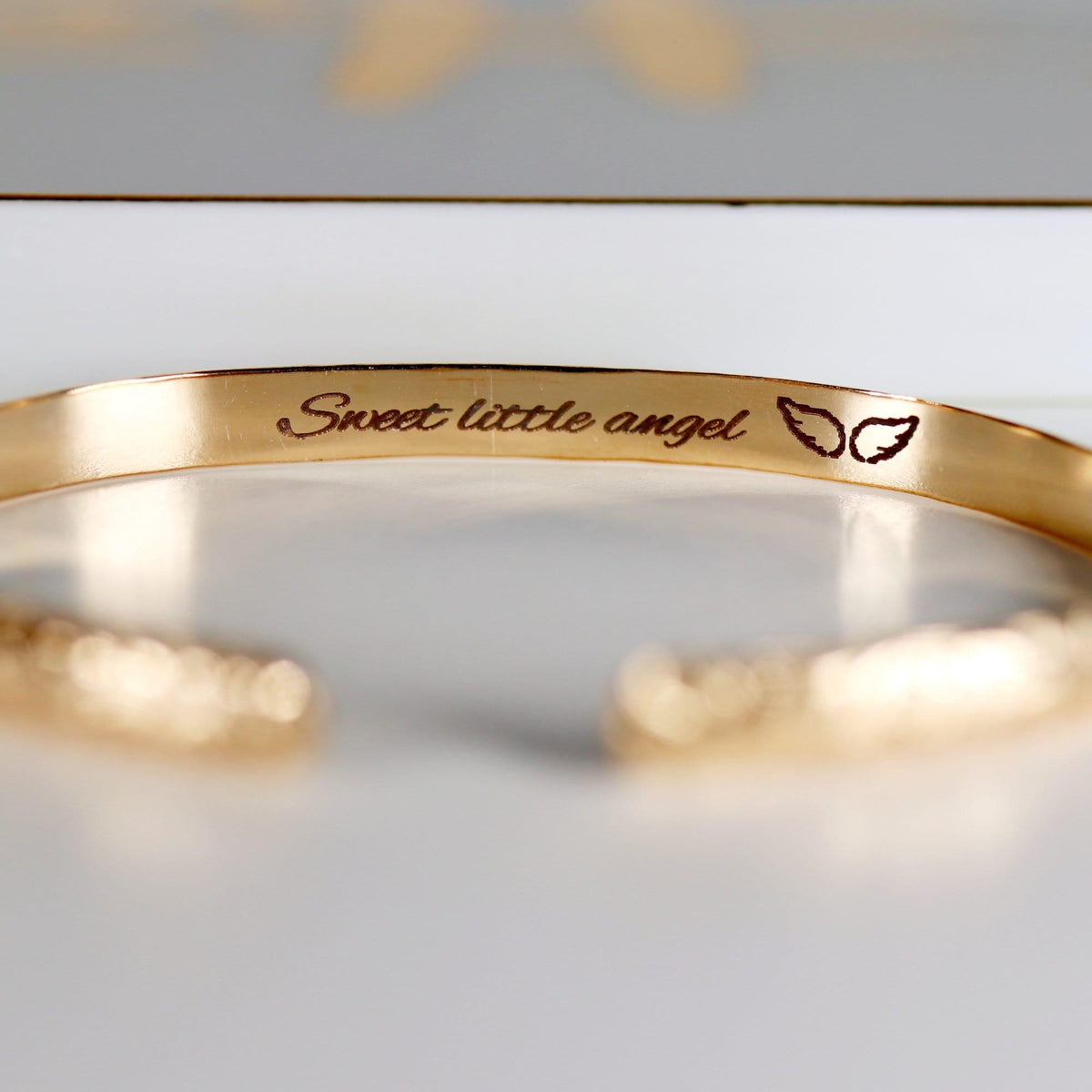 A gold cuff bracelet with &amp;quot;Sweet little angel&amp;quot; and two small wings engraved on the inside.