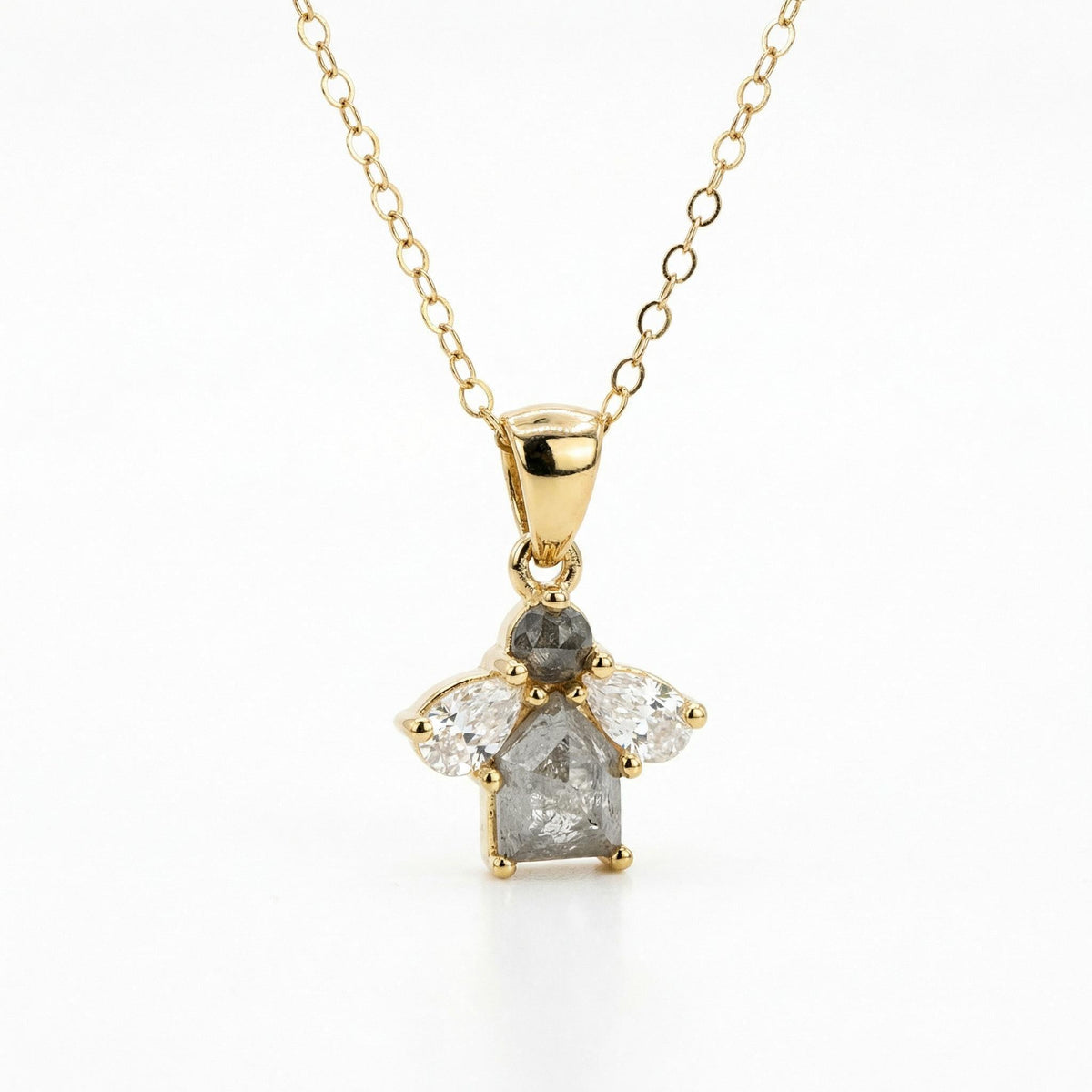 A close-up of a gold chain necklace with a cluster pendant featuring a gray round diamond, a gray rectangular diamond, and two clear pear-shaped diamonds.