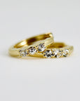 Two small gold huggie hoop earrings, each with three clear round stones set into the front, on a white background.