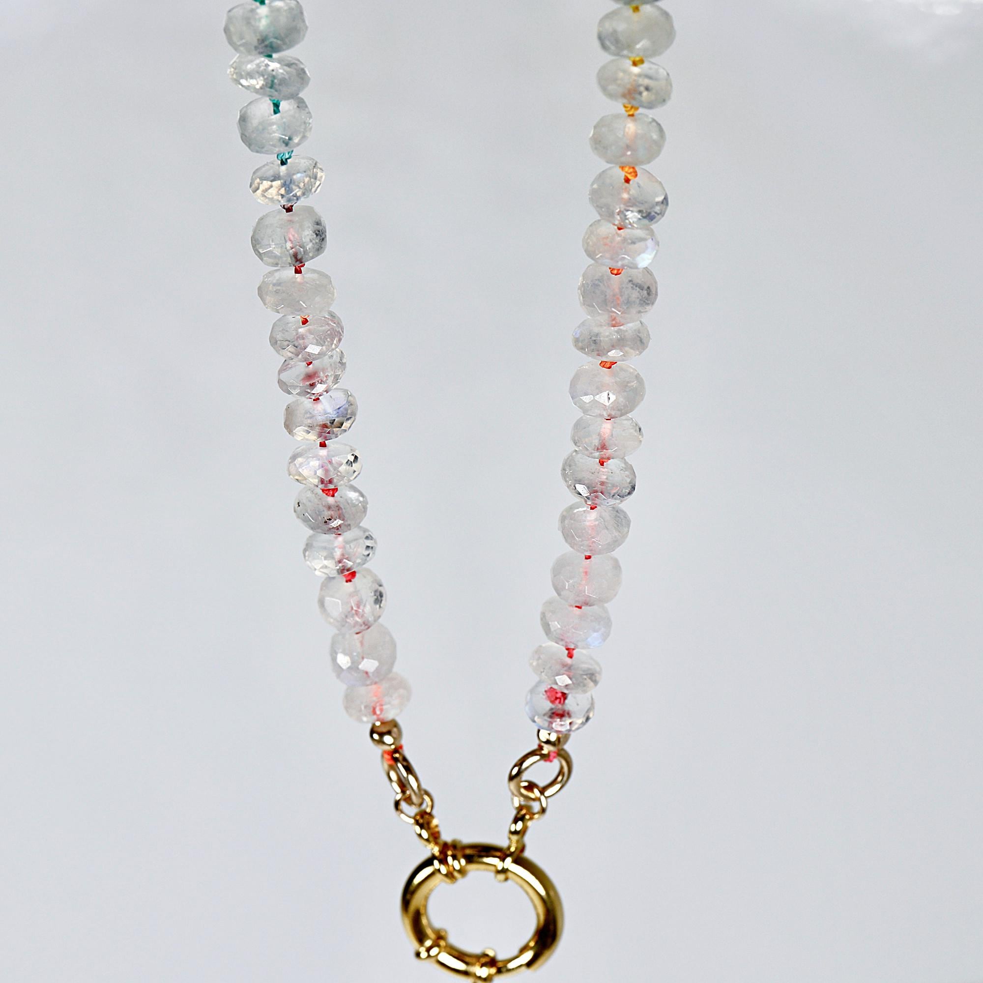Hand knotted moonstone rondelle necklace on rainbow silk with gold filled figure eight clasp laid flat on white background.