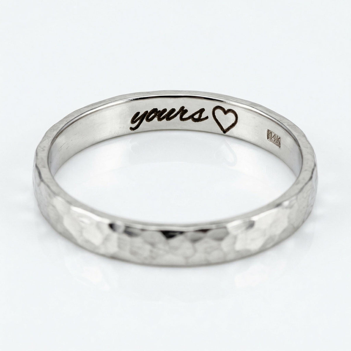 A white gold hammered band ring with &amp;quot;yours&amp;quot; and a heart engraved on the inside.