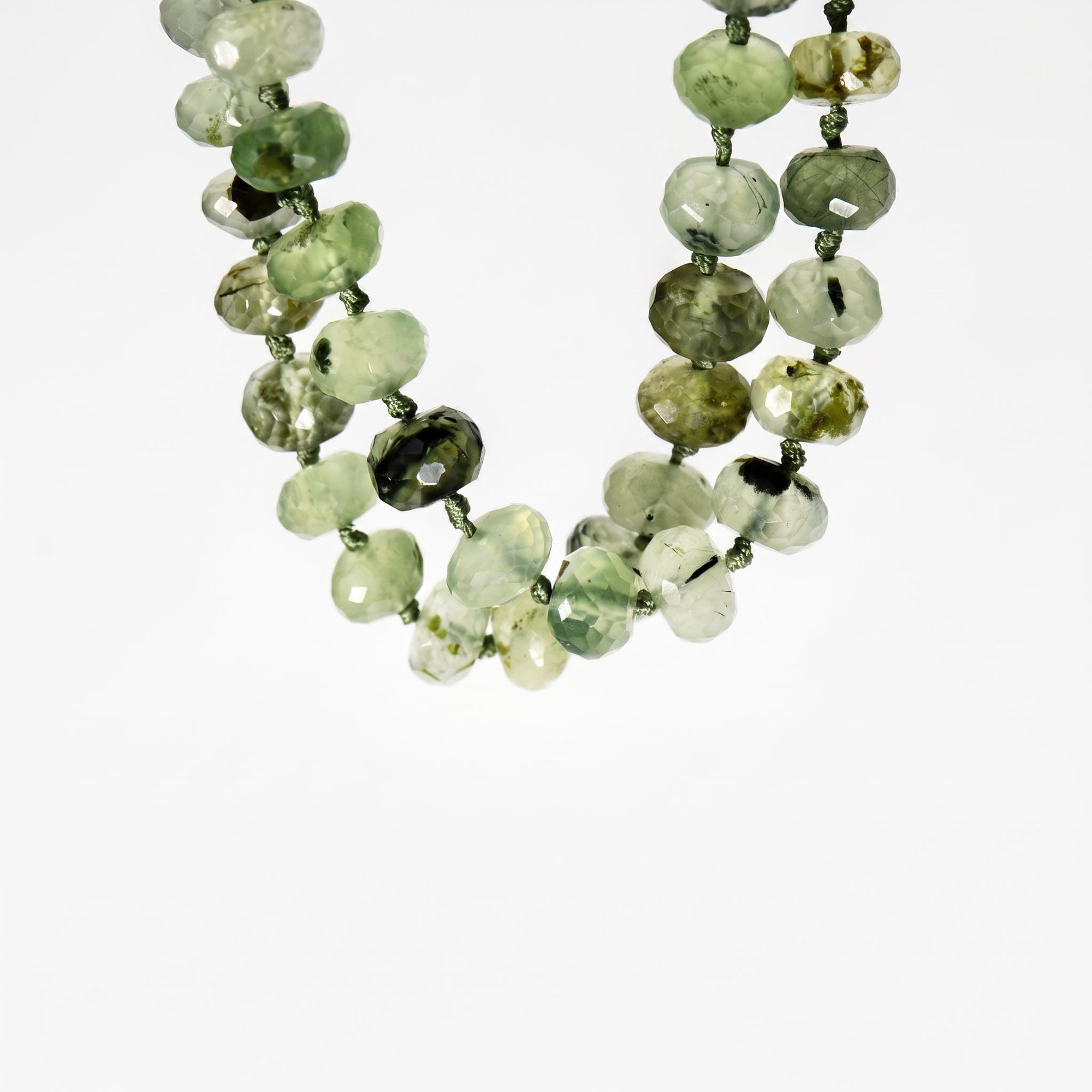 Green prehnite 7mm faceted rondelle necklace on silk with gold filled figure eight charm holder clasp laid flat on white background.