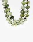 Green prehnite 7mm faceted rondelle necklace on silk with gold filled figure eight charm holder clasp laid flat on white background.