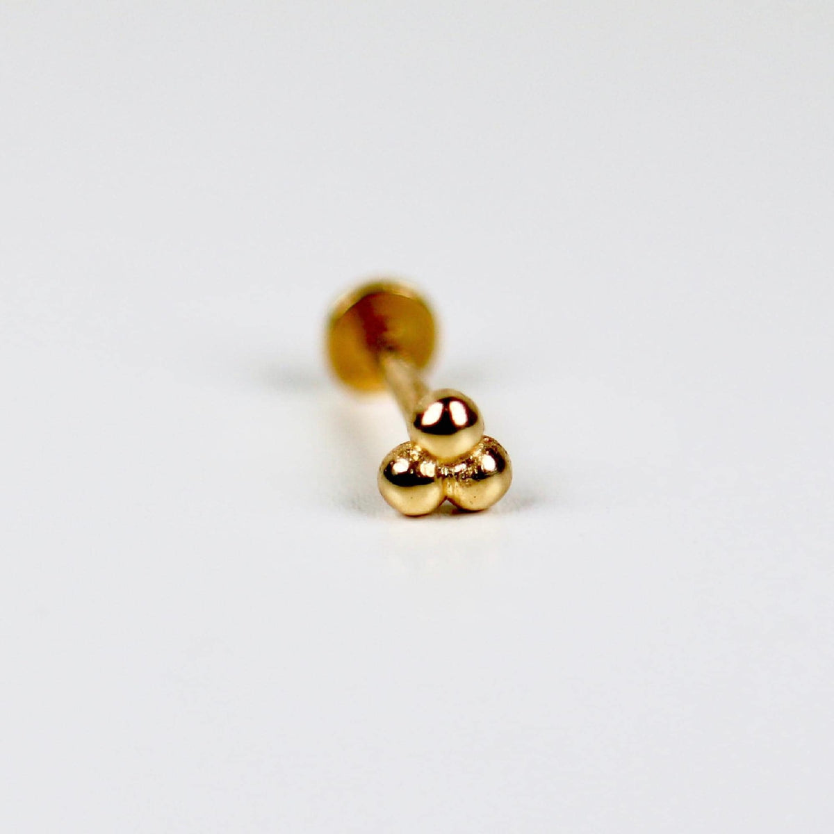Macro view of the gold trinity ball earring top, angled to show its three clustered spherical beads.