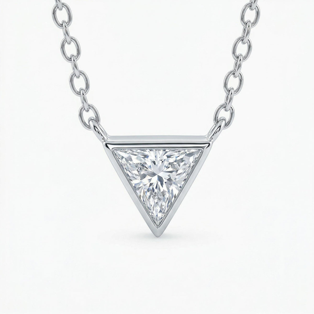 A close-up view of a silver-toned necklace featuring a bezel-set triangle pendant against a plain white background.