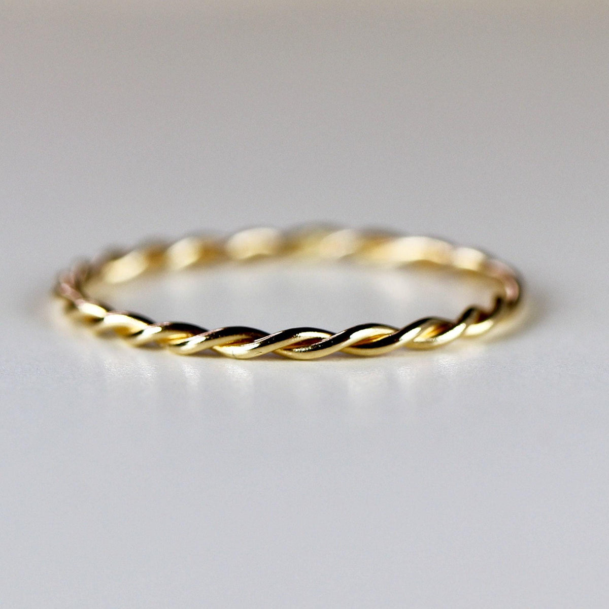 A single gold twisted rope ring is centered on a plain white background.