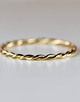 A single gold twisted rope ring is centered on a plain white background.