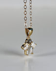 A close-up of a gold chain necklace with a cluster pendant featuring a gray round diamond, a gray rectangular diamond, and two clear pear-shaped diamonds.