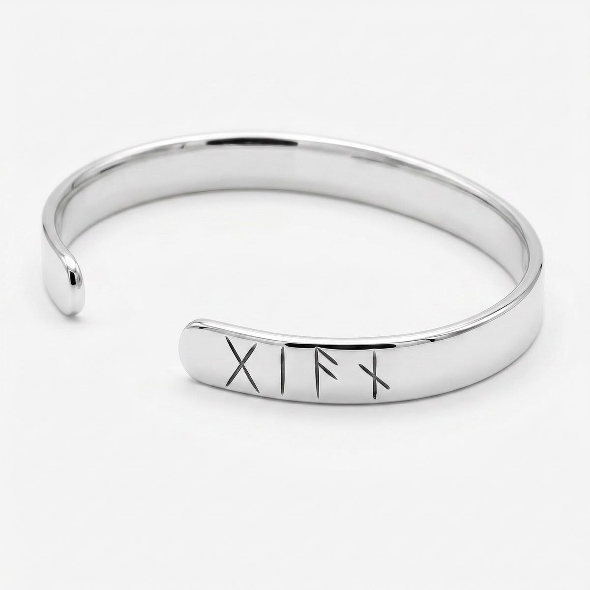 A polished silver-colored metal open cuff bracelet displayed alone on a plain white background with engraved rune symbols near one end.
