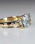 The opposite side profile of the gold ring on a white surface, showing the hammered band texture and small flush-set accent diamonds.
