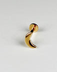 A gold crescent moon flat back labret stud earring angled on a light surface.