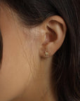 Close-up view of a person wearing a small star-shaped stud earring in the earlobe.
