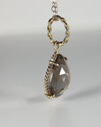 Profile view of a pear-shaped faceted smokey quartz pendant featuring a textured rope-style gold bale and trim.