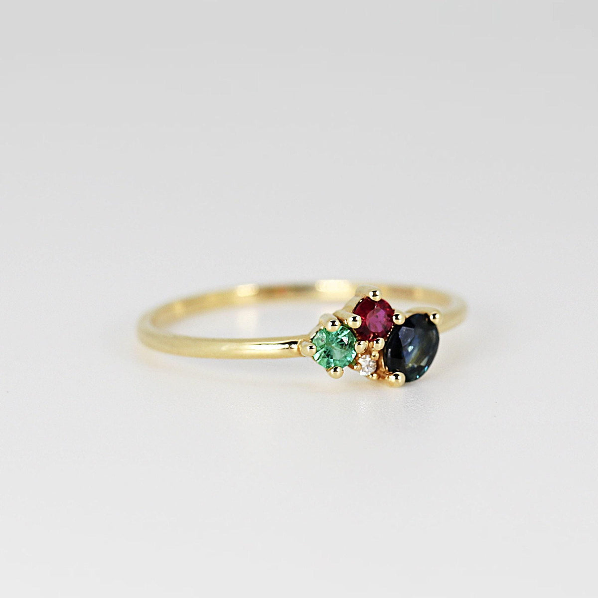 Three-quarter perspective of the gold multi-stone ring against a solid neutral white background.