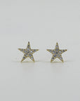 A pair of gold star-shaped stud earrings inset with small clear stones, presented on a light background.