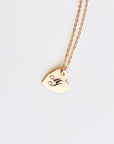 An engraved gold heart pendant on a delicate chain against a plain white background.