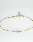The complete gold bracelet arranged in an oval shape on a plain surface, featuring a diamond cross and an adjustable extension chain.
