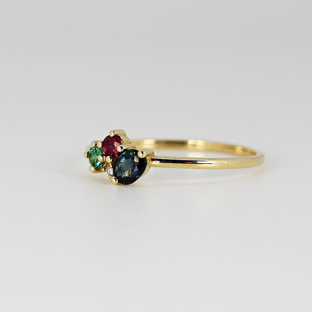 Side profile view of the gold ring highlighting the cluster setting with the green stone in the foreground.