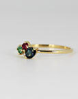 Side profile view of the gold ring highlighting the cluster setting with the green stone in the foreground.