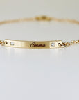 A macro photograph focusing on the engraved name Emma and two flush-set diamonds on a curved gold bar.