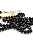 A coiled black faceted bead necklace featuring a gold extender chain with heart details.