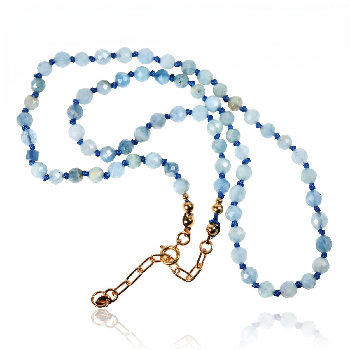 A hand-knotted light blue faceted gemstone bead necklace with a gold-colored extender chain laid flat on a white surface.