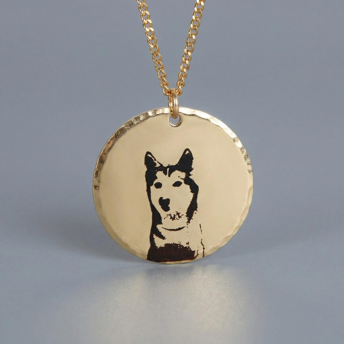 A gold-filled hammered coin pendant with an engraved portrait of a husky dog on a chain.