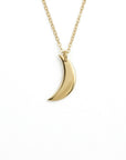 A product studio shot of a gold crescent moon pendant on a chain against a plain white background.