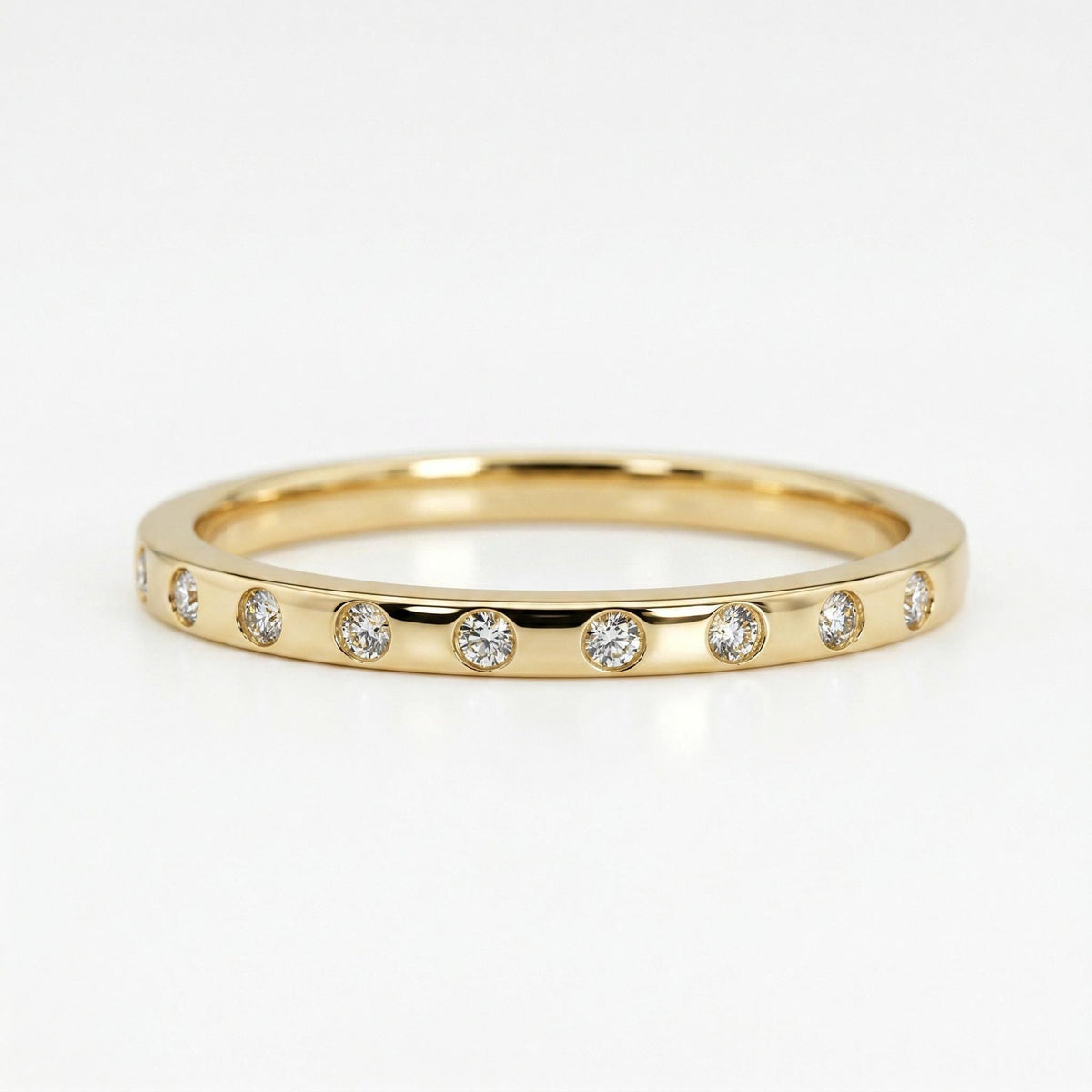 A gold band set with small flush round diamonds along the top surface against a plain light background.