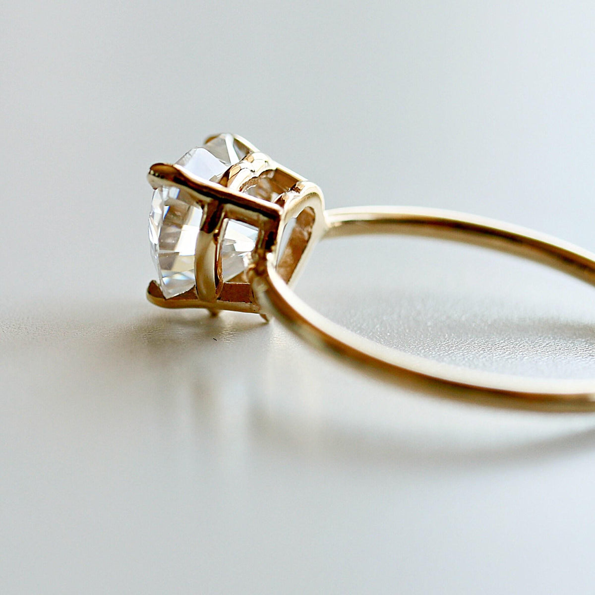 Side view of the gold ring highlighting the basket setting holding the faceted gemstone.